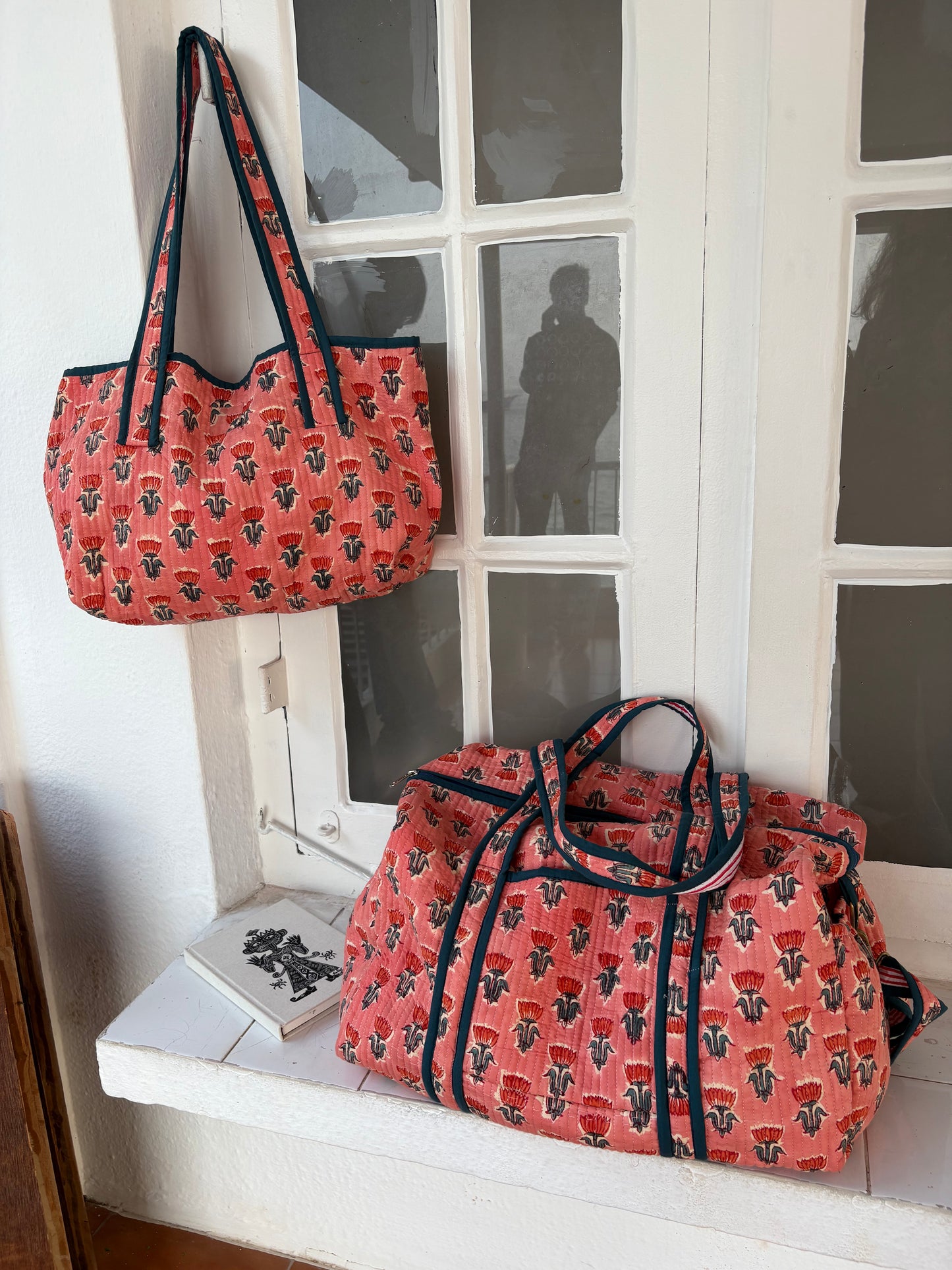 Two patterned bags on a windowsill with a white frame.