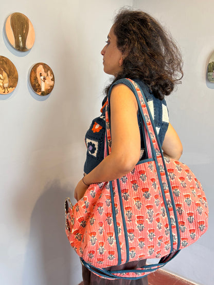 Woman carrying a large pink and blue patterned bag in an art gallery.