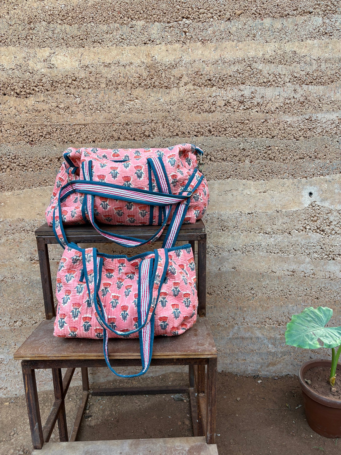 Pink patterned bags on a wooden chair against a textured wall.